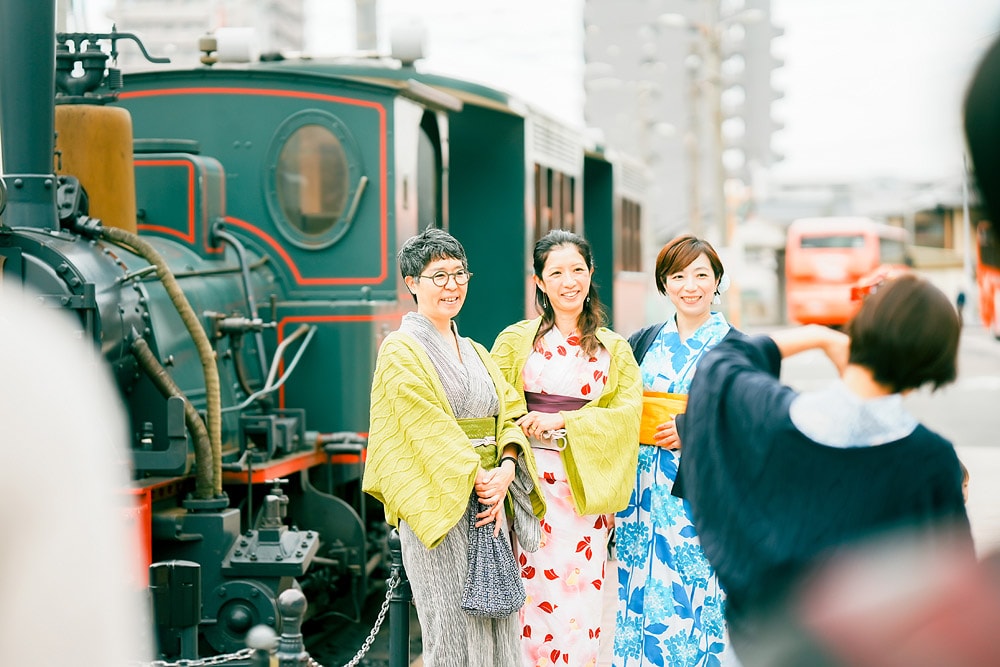 道後駅前の名物「坊っちゃん列車」を背景に、山本邦子先生（中央）と撮影。